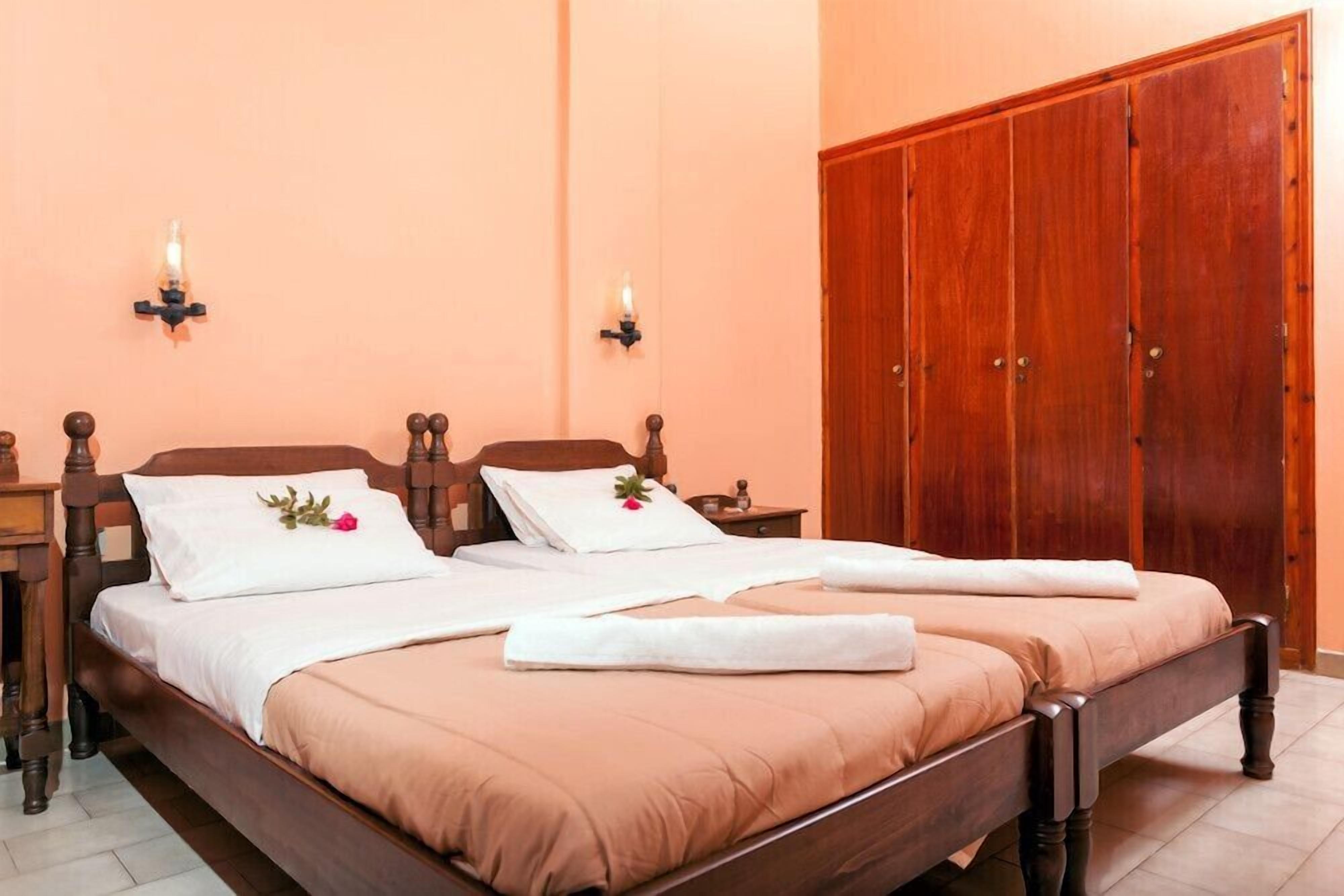 A double bed with a wooden frame, two nightstands, a wardrobe, and wall sconces.