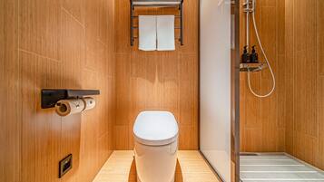 A modern bathroom with a toilet, a towel rack, a shower, and a toilet paper holder.