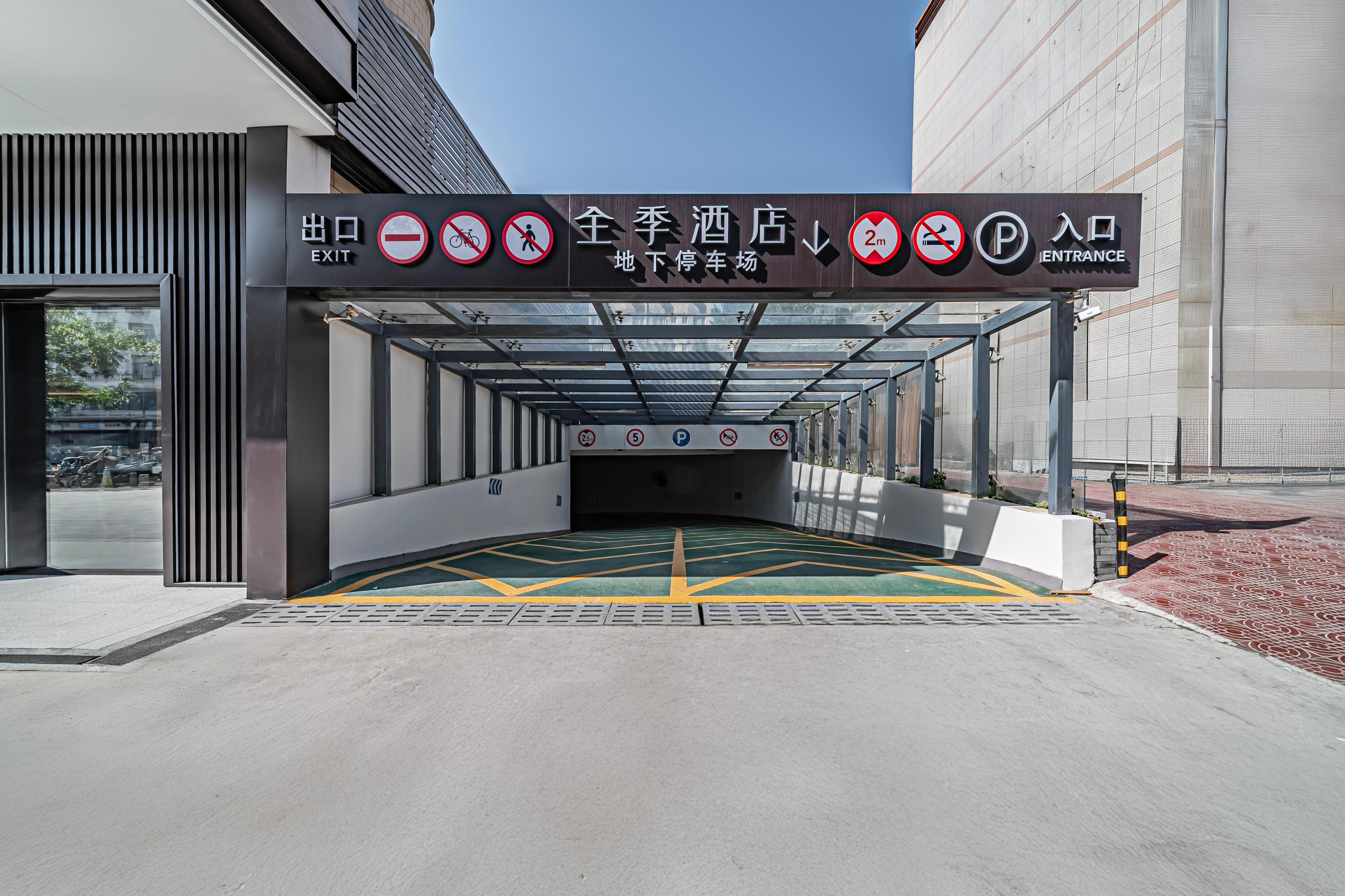 A hotel entrance with clear signage indicating an exit, no entry for bicycles and pedestrians, and a parking area with a 2m and 5m restriction.