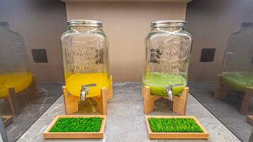 To glasdispensere med træsokler og grønne græsdug, mærket 'Yorkshire' og 'Estonia', på en marmor bordplade.
