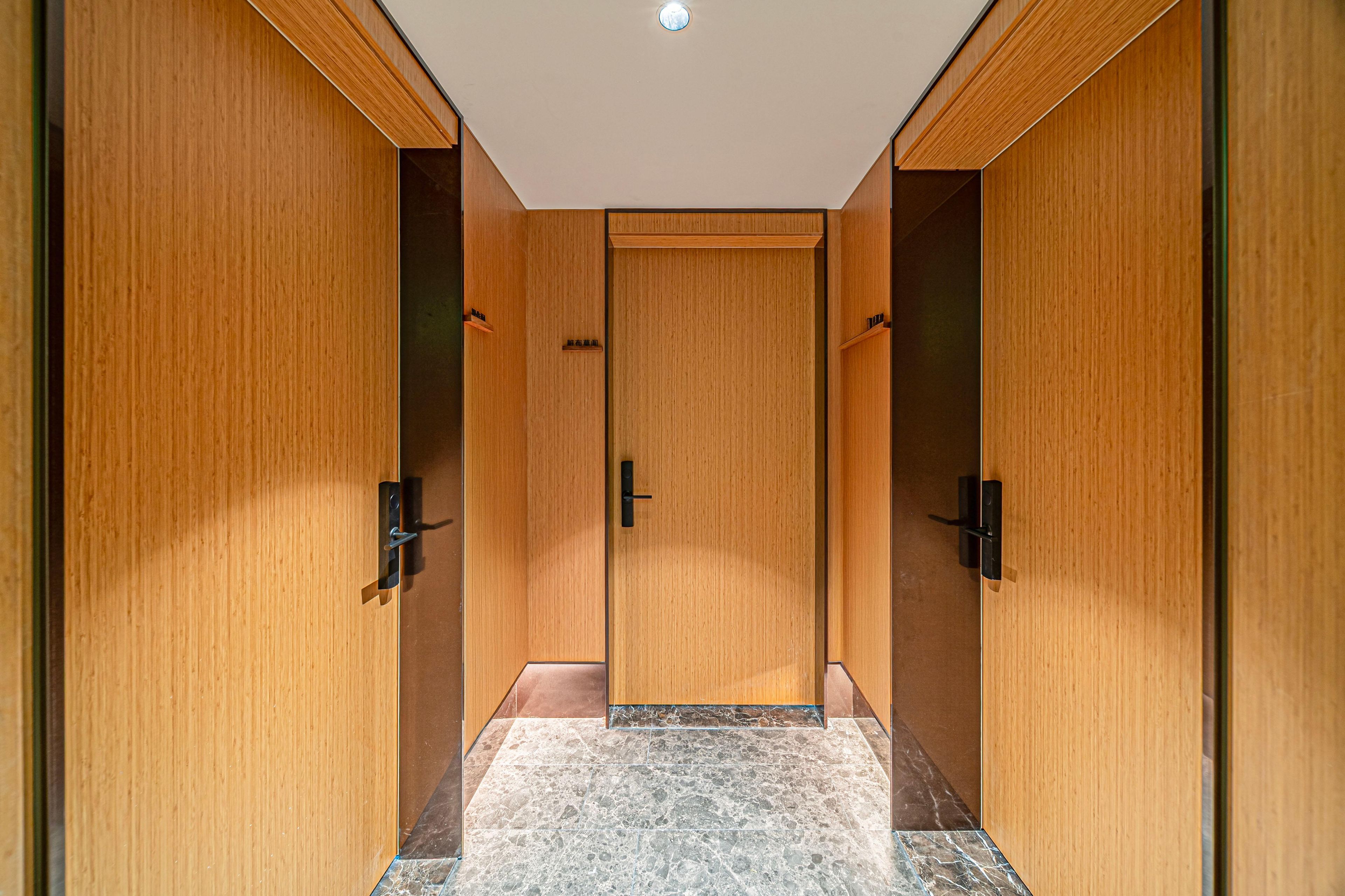 A hallway with wooden doors and a marble floor.