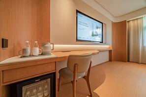 A hotel room with a wooden desk, a chair, a television mounted on the wall, and a window with curtains. - JI Hotel (Xi'an)