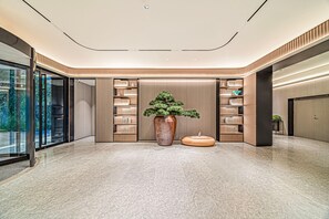 A modern lobby with a large potted plant, bookshelves, and a marble floor. - JI Hotel (Xi'an)