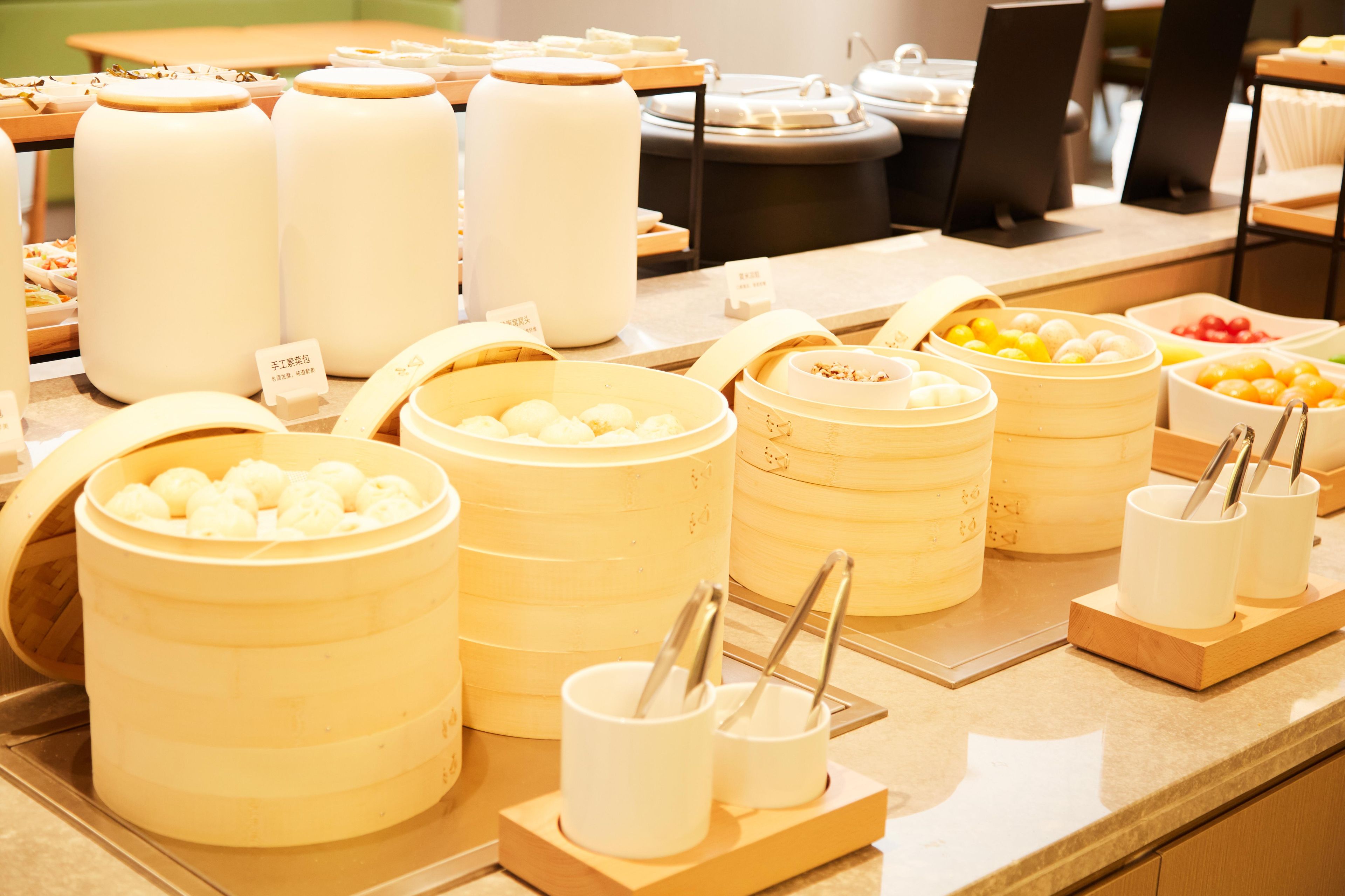 A buffet with various food items in containers, including steamed buns and other dishes.