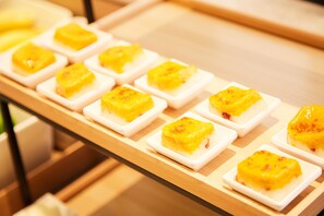 A series of square white dishes with yellow toppings arranged on a wooden surface. - JI Hotel (Xi'an)