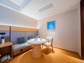 A modern room with a round wooden table, a bench with cushions, a wall-mounted shelf, and a framed picture. - JI Hotel (Xi'an)