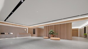 Una moderna zona de recepción con mostrador, una planta grande en maceta y un diseño minimalista.