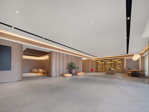 Eine großzügige Lobby mit modernem Design, ausgestattet mit einer Sitzecke, einem Empfangstresen und einem großen Bücherregal.
