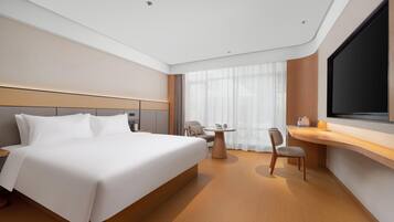 A modern hotel room with a large bed, a desk, and a TV.