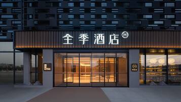 A hotel entrance with a modern facade, large glass doors, and a sign indicating a hotel.