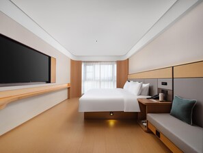A modern hotel room with a large bed, a flat-screen TV, a desk, and a sofa. - JI Hotel (Xi'an)