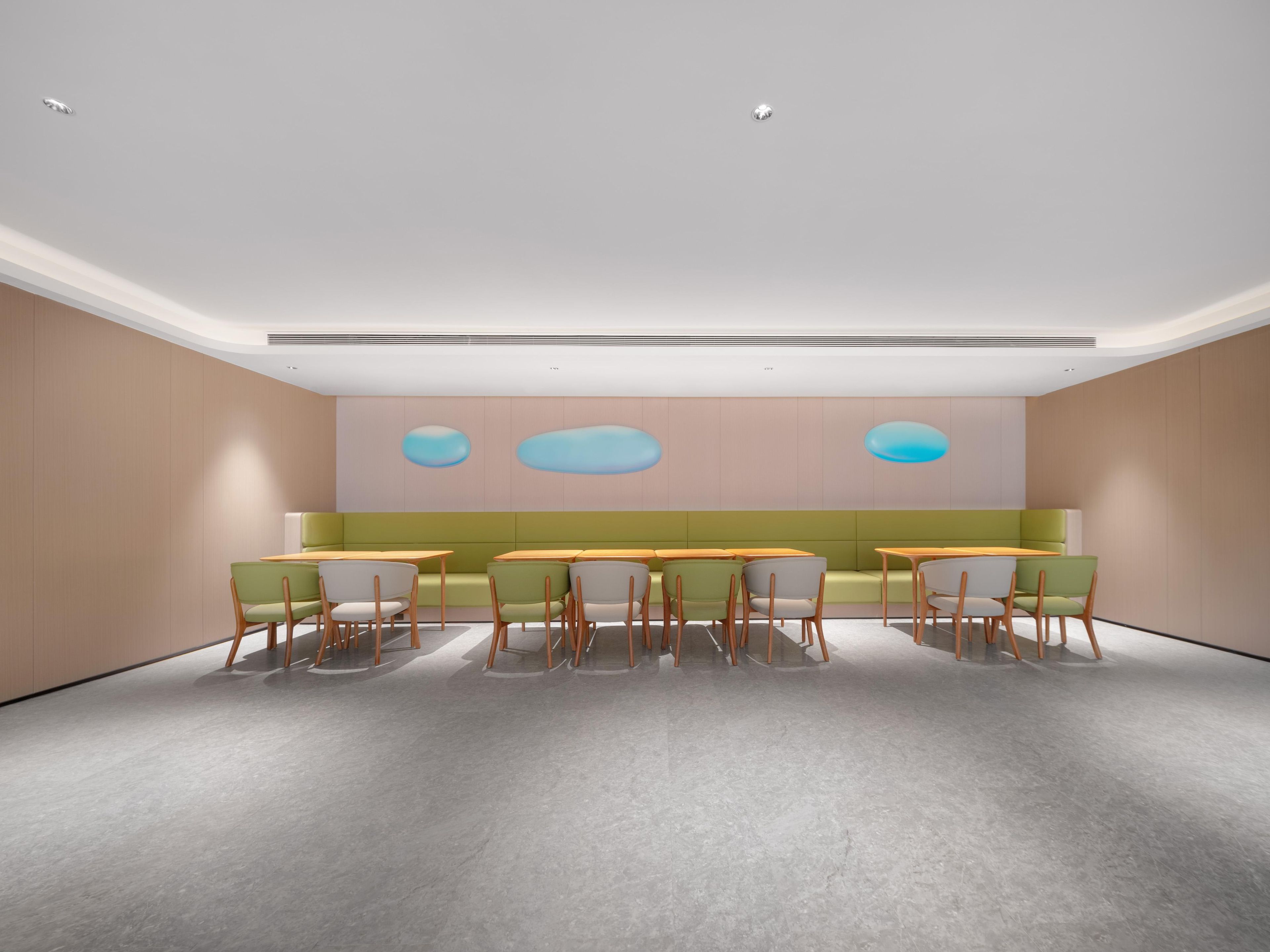 A modern conference room with a neutral color palette, featuring a long table with chairs and a seating area with a sofa.