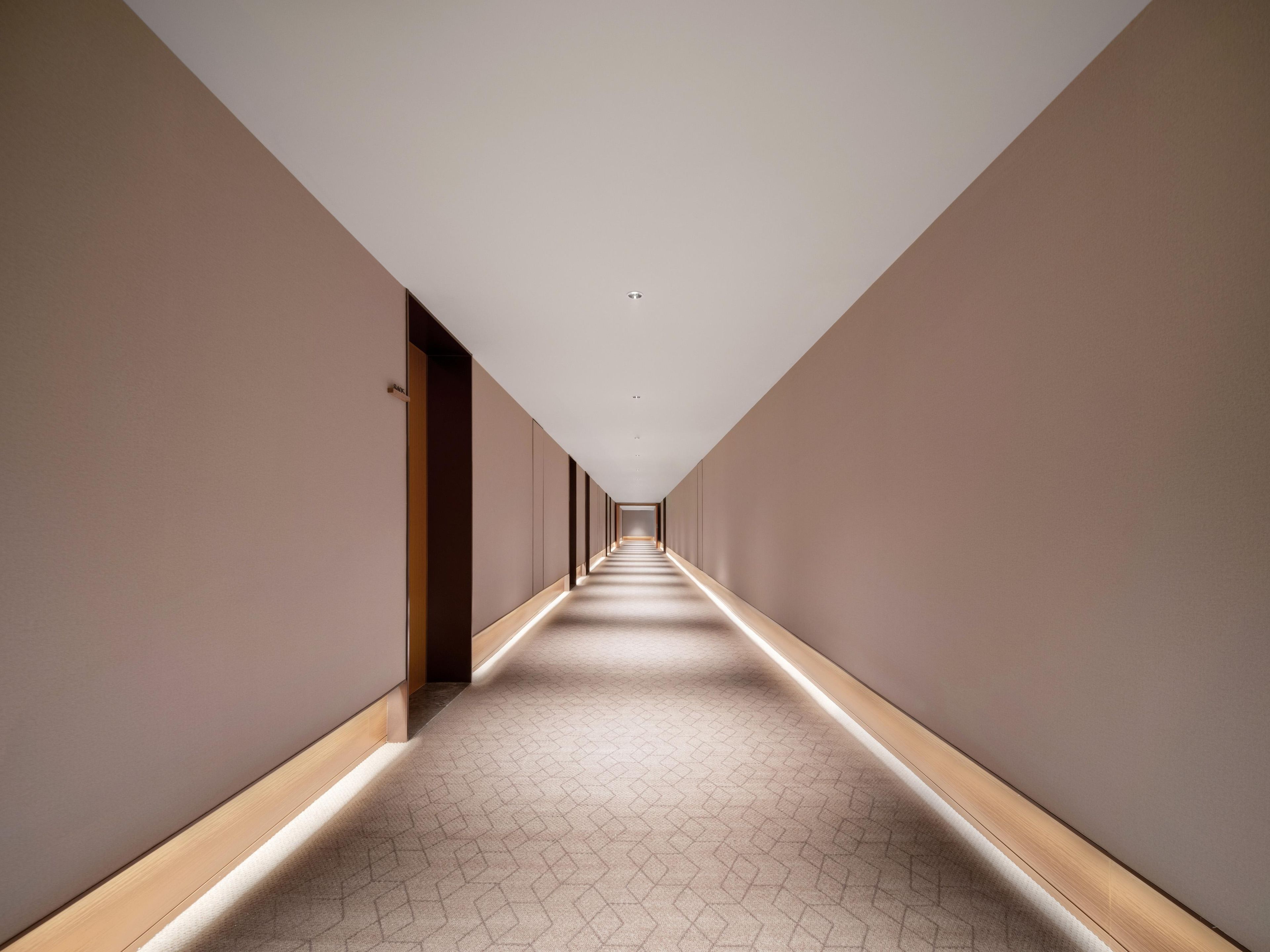 A long, narrow hallway with a patterned carpet and wooden trim.