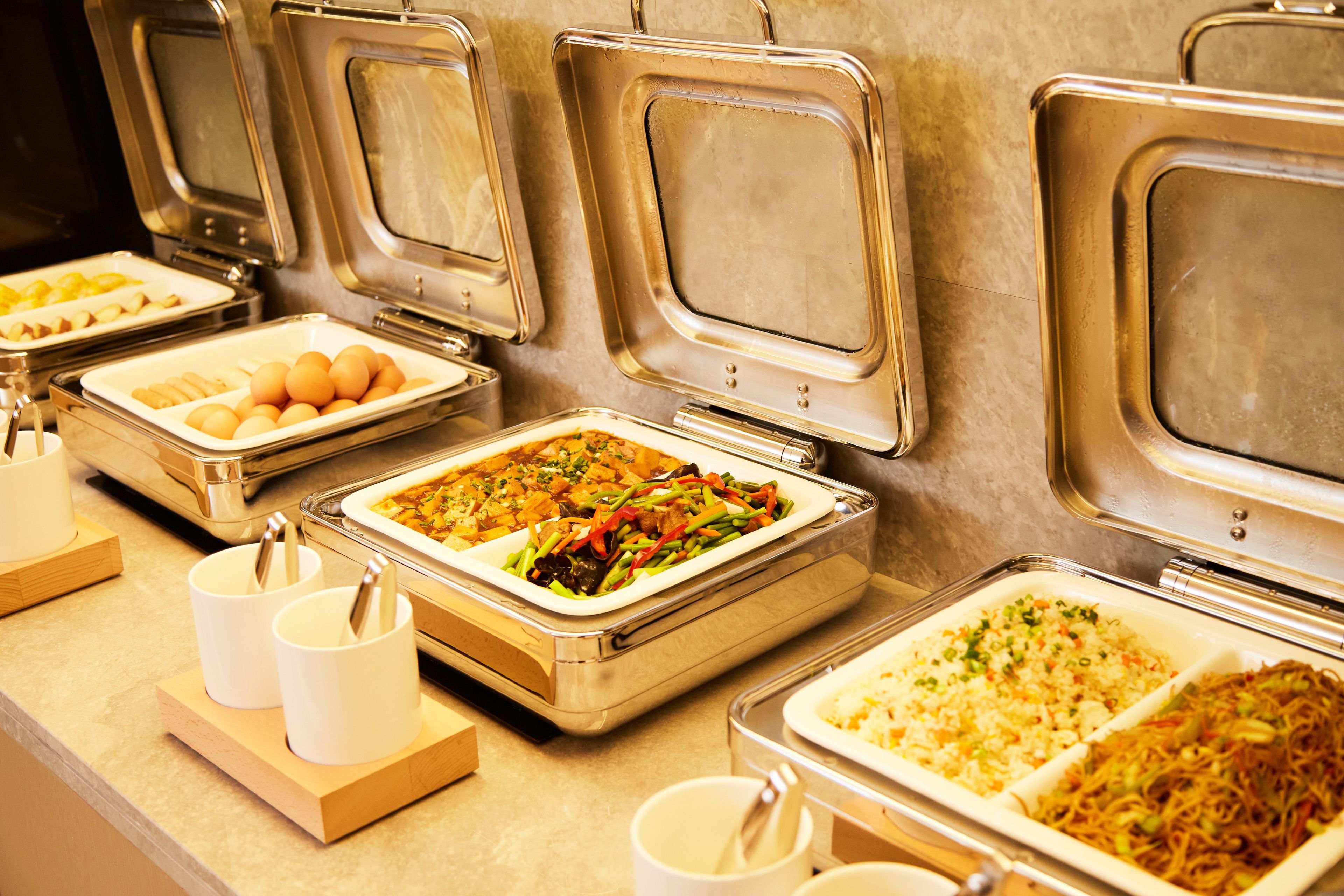 A buffet setup with various food items and utensils.