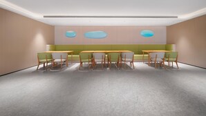 Un salón de conferencias moderno con una paleta de colores neutros, con una larga mesa, sillas y un área de estar con un sofá.