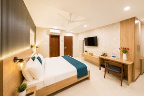 A modern hotel room with a bed, desk, TV, and a ceiling fan. - Harvey's Hotels Gachibowli (Hyderabad)