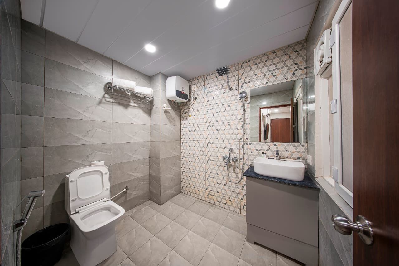 A bathroom with a toilet, sink, shower, and tiled walls.