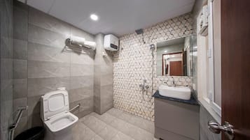 A bathroom with a toilet, sink, shower, and tiled walls.