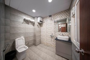 A bathroom with a toilet, sink, shower, and tiled walls. - Harvey's Hotels Gachibowli (Hyderabad)