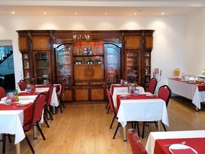 A dining area with multiple tables set for service, a decorative wooden cabinet with glass doors, and a buffet table with food and drinks. - Gã¤stehaus Karl August (Fohnsdorf)