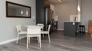 Una cocina moderna con refrigerador, horno y pileta. Hay un comedor con mesa y sillas.