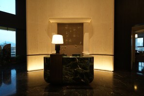 A lobby area with a marble reception desk, a wall-mounted lamp, and a decorative panel with a dragon design. - Quanzhou West Street Huajianfu · Liuxi (Quanzhou)