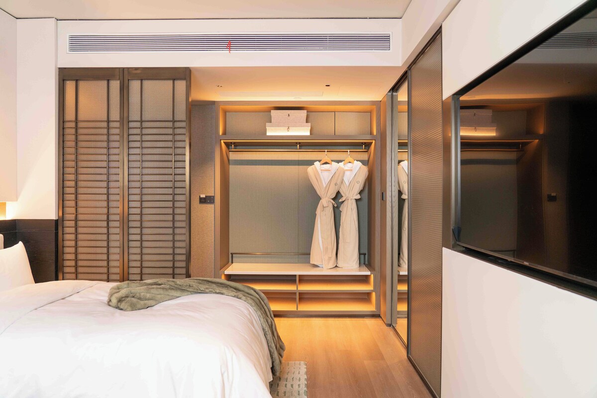 A hotel room with a bed, a walk-in closet, and a television.