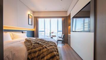 Habitación de hotel con una cama grande, vistas a la ciudad y un comedor con mesa y sillas.