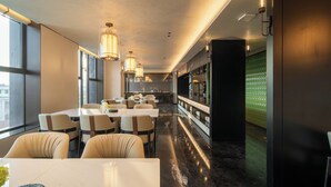 A modern restaurant interior with high ceilings, pendant lighting, and a long counter with seating.