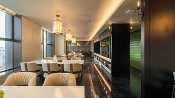 Un restaurante moderno con techos altos, iluminación colgante y una barra larga con asientos.