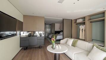 Una habitación de hotel moderna con kitchenette, un sofá, una pequeña mesa redonda y un vestidor.