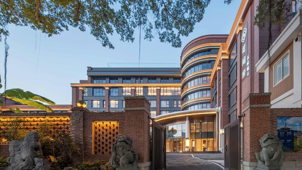 A modern building with a curved facade, large windows, and a gated entrance.