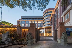 A modern building with a curved facade, large windows, and a gated entrance. - Quanzhou West Street Huajianfu · Liuxi (Quanzhou)