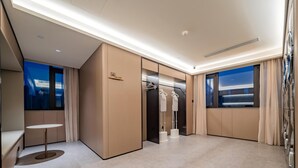 A modern hotel room with a large bed, a bedside table, a wardrobe, and a view of the cityscape.