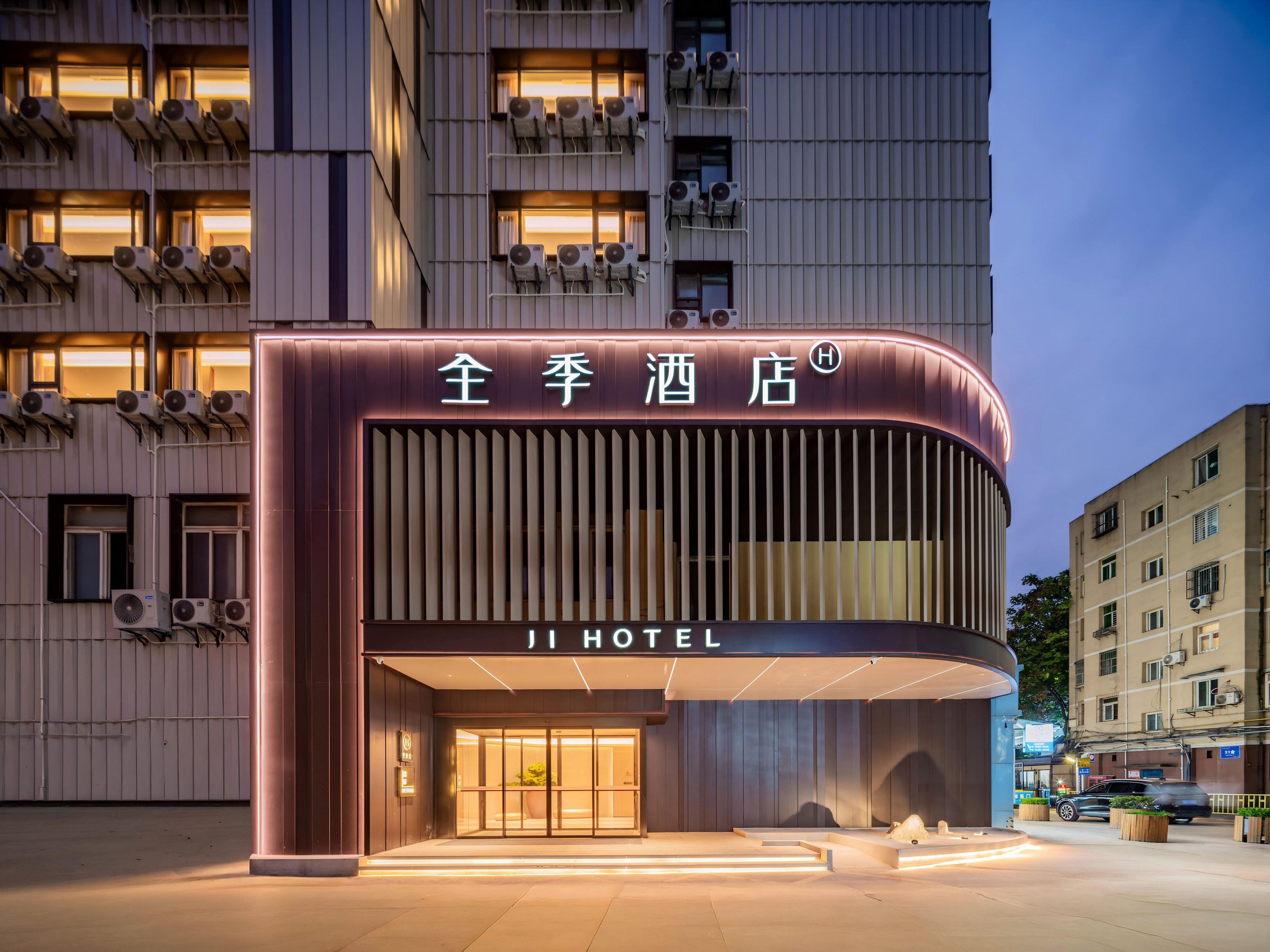 Een hotelgevel met een modern ontwerp, bestaande uit een gebogen façade en verlichte signage.