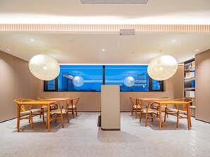 A modern interior with a central reception desk, two dining areas with wooden tables and chairs, and large windows offering a city view. - JI Hotel Xian Jiaotong University Xingqing Campu (Xi'an)