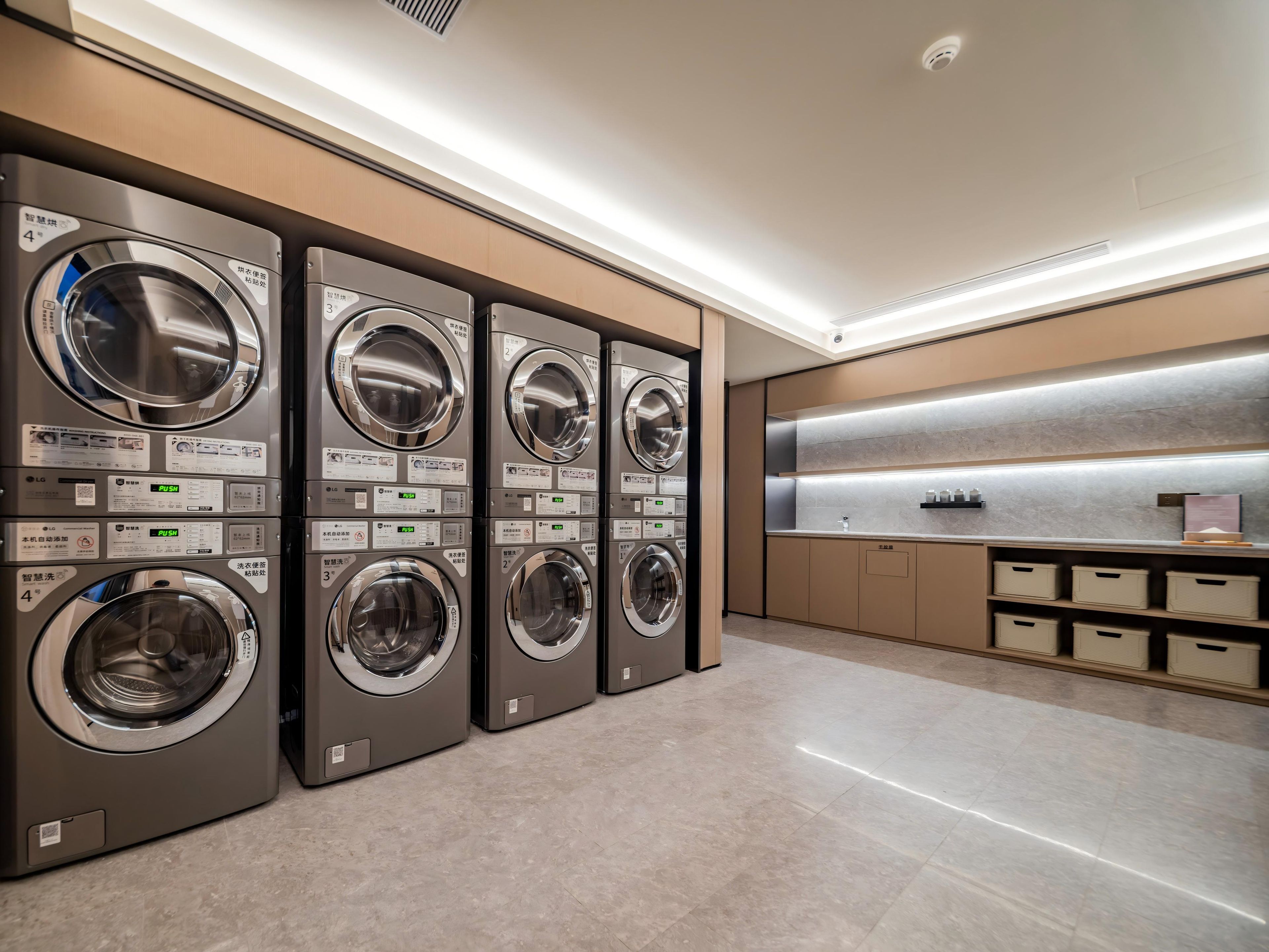 Een moderne wasserette met vier wasmachines, een wasbak en opbergkasten.