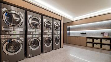 Een moderne wasserette met vier wasmachines, een wasbak en opbergkasten.