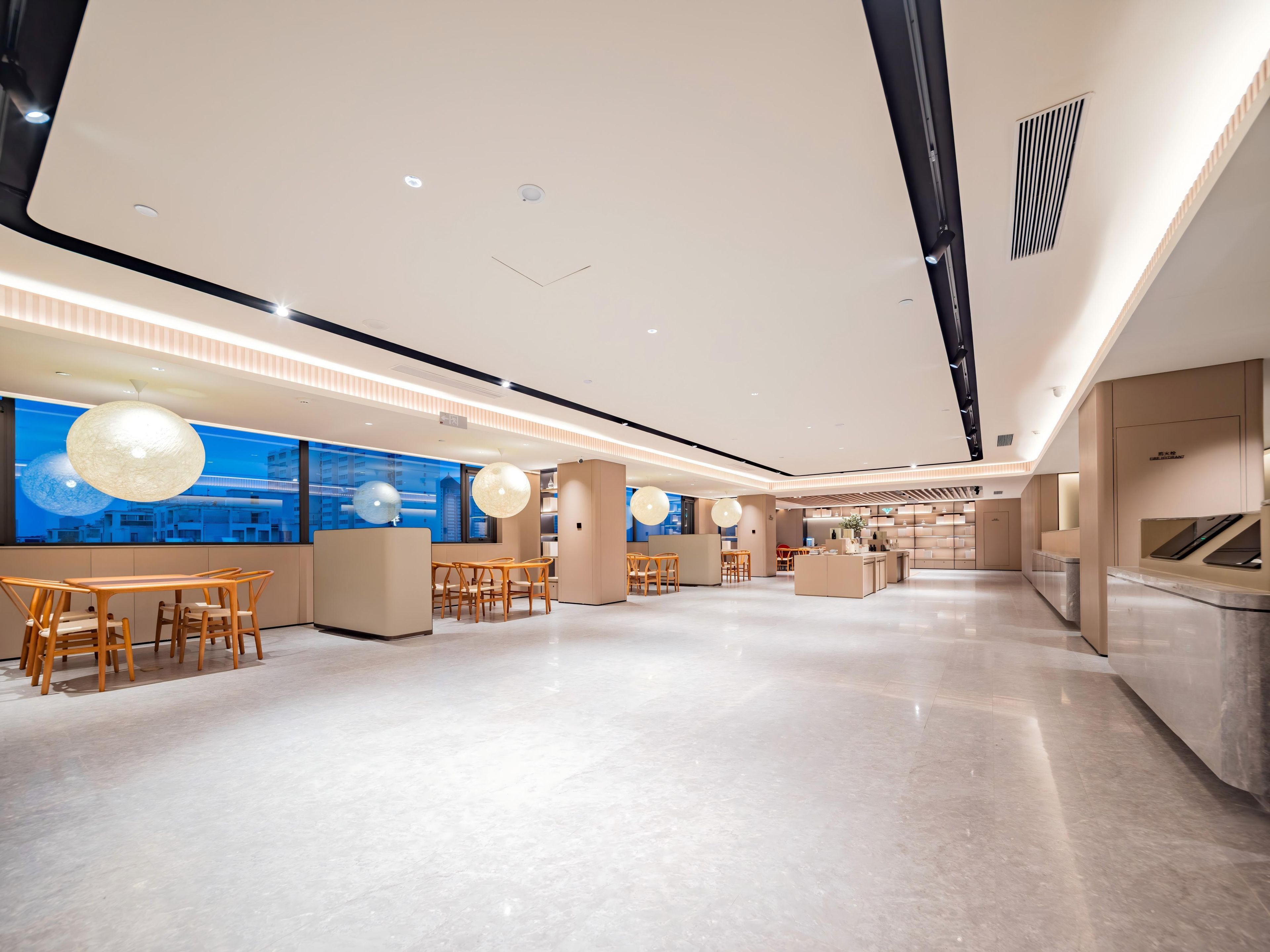 A spacious hotel lobby with a modern design, featuring a long reception desk, seating areas, and large windows with a city view.