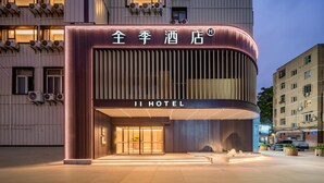 A hotel entrance with a modern design, featuring a curved facade and illuminated signage.