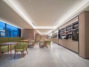 A modern interior with a long dining area, green seating, and a kitchen counter with appliances. - JI Hotel Xian Jiaotong University Xingqing Campu (Xi'an)