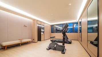 A modern fitness room with a treadmill, a bench, and a mirrored wall.
