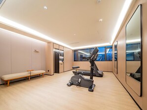 A modern fitness room with a treadmill, a bench, and a mirrored wall.