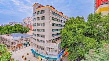 A multi-story building with a curved facade, surrounded by greenery and other buildings.