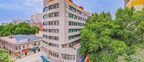 A multi-story building with a curved facade, surrounded by greenery and other buildings.