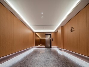 A modern elevator with a metallic finish, a hallway with wooden paneling, and a tiled floor. - JI Hotel Xian Jiaotong University Xingqing Campu (Xi'an)