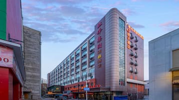 A multi-story hotel with a prominent curved facade, multiple balconies, and a ground-level entrance with signage.