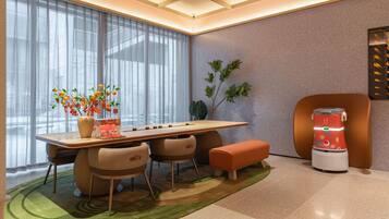 A modern room with a dining table, chairs, a bench, a coffee machine, and a plant.