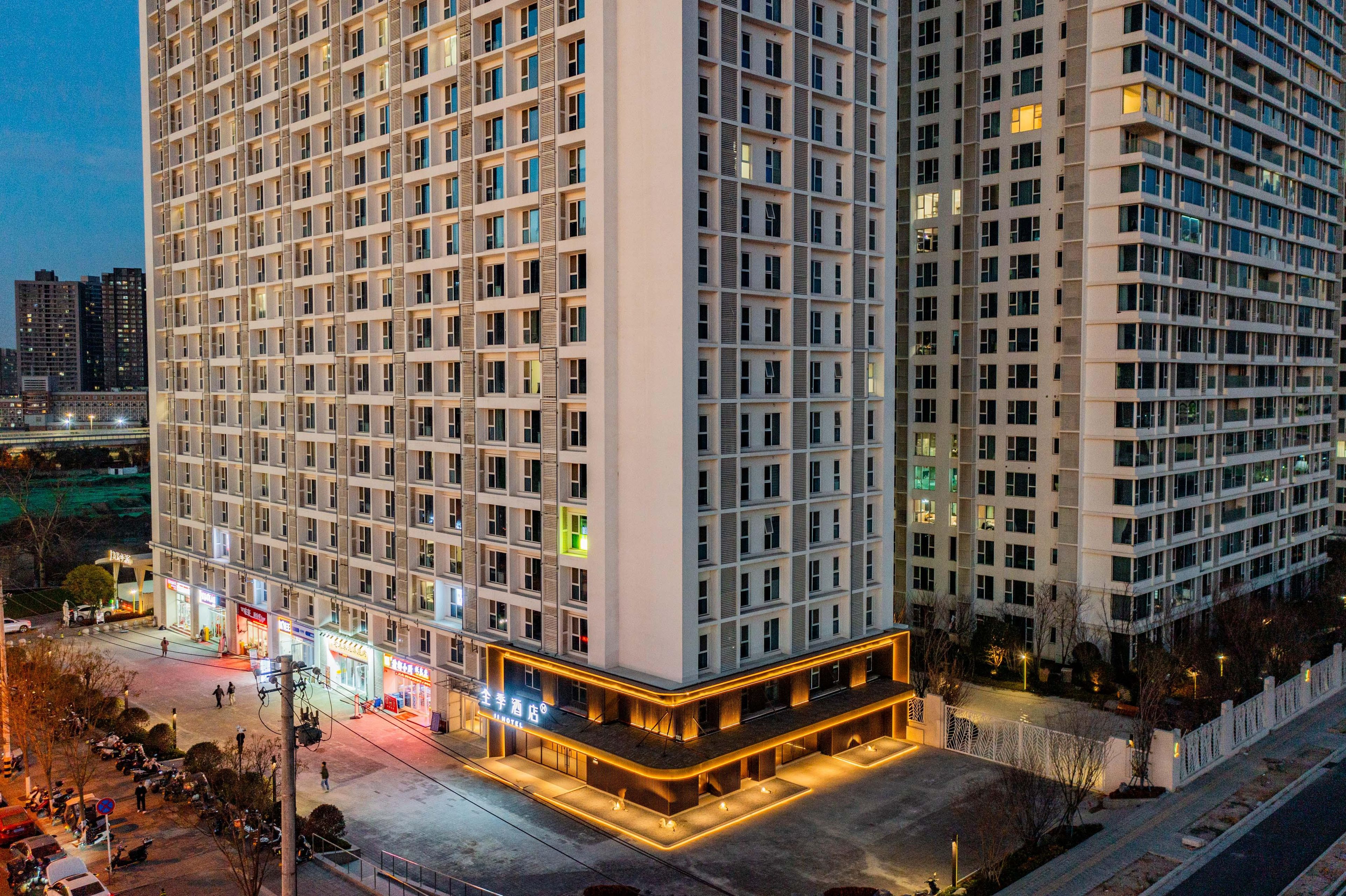 Un hotel de gran altura con varios pisos, una zona comercial en la planta baja y un estacionamiento.