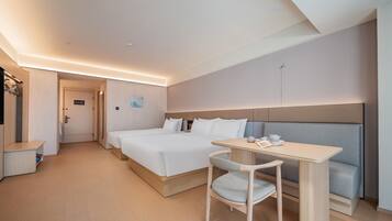 A hotel room with a bed, a desk, and a chair. There is a door leading to another room.